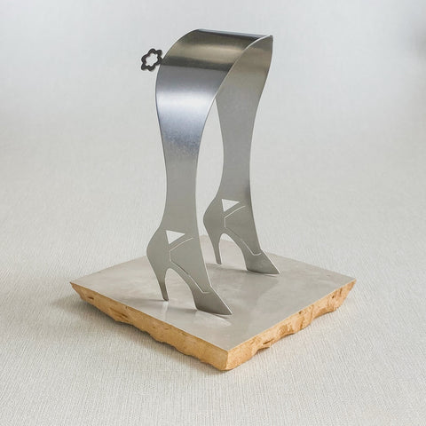 Stainless steel serving tongs in high heel design standing up on white ceramic tile