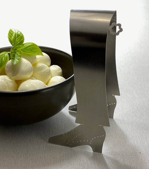 Stainless steel shoe shaped Stepping Out serving tongs next to bowl of bonconcini balls with basil