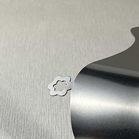 Close up of flower detail on stainless steel serving tongs lying on its side