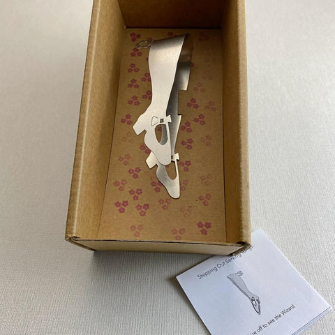 Stainless steel mini tongs lying in cardboard gift box with floral pattern and care slip