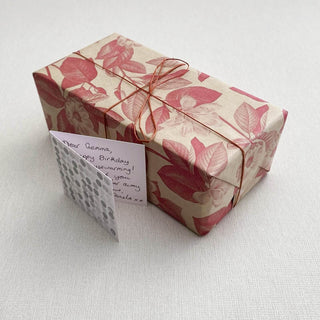 Wrapped between you and me gift with handwritten message card and pink botanical paper