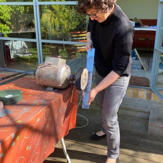 Between You and Me maker polishing a stainless steel serving piece on an outdoor studio polishing wheel