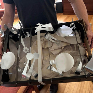 Box of handcrafted stainless steel Between You and Me serving pieces being carried from the studio