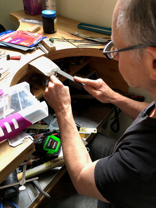 Artisan working at the bench on a handcrafted stainless steel serving piece in the Between You and Me studio