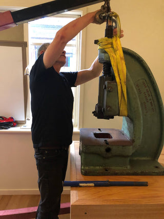 Studio maker setting up a fly press used in the handcrafted production process