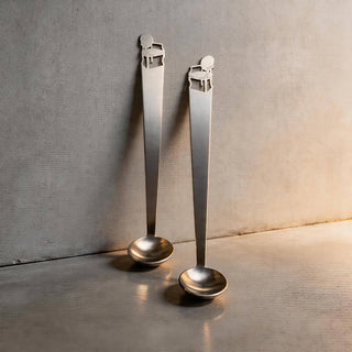 Pair of Cabriole stainless steel tiny serving ladles on a grey stone surface