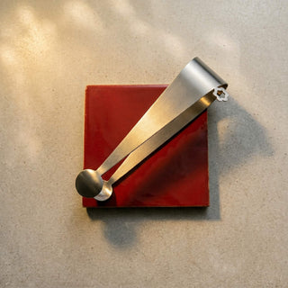 Handcrafted Dome stainless steel serving tongs displayed on red ceramic tile