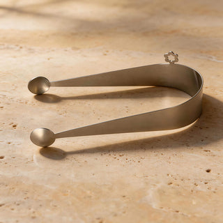 Dome stainless steel serving piece resting on warm travertine stone surface
