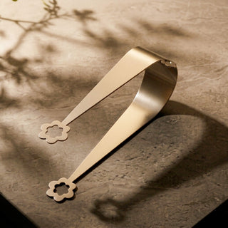 Stainless steel Flowers serving piece on stone surface with soft botanical shadows