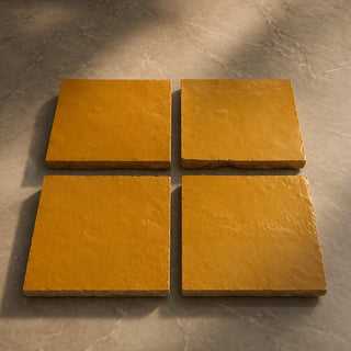 Set of four Golden Sun handcrafted ceramic table tiles with warm ochre glaze and softly uneven surfaces