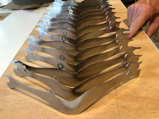 Row of High Heel stainless steel serving pieces arranged on a studio bench