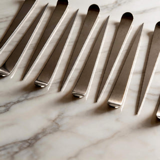 Stainless steel Maestro cocktail picks arranged in a repeating pattern on marble