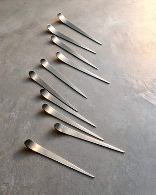 Maestro stainless steel cocktail picks arranged in a soft diagonal pattern on stone surface