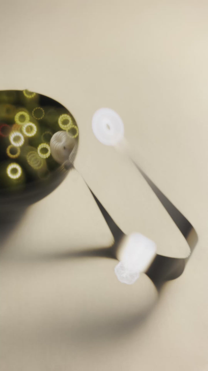 Atmospheric video of the Circles stainless steel serving piece beside a bowl of green olives, with soft light twinkling on the metal surface 
