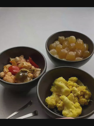 Video of a hand using a Maestro stainless steel cocktail pick to lift a pickled onion from a bowl, with small dishes of olives and vegetables nearby.