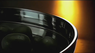 Video of an Off to See the Wizard handcrafted stainless steel serving piece lifting a green olive from a bowl, showing the shoe-shaped detail in use.
