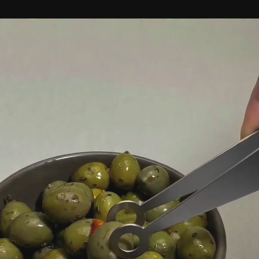 Video of a Circles handcrafted stainless steel serving piece lifting a green olive from a bowl, showing the round cut-out detail in use.