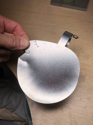 Hand holding Those Two stainless steel salad server showing the gently smiling sculptural face detail