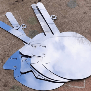 Stack of Those Two stainless steel salad servers with sculptural face details outside the studio